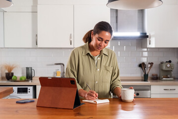 Woman taking notes near tablet