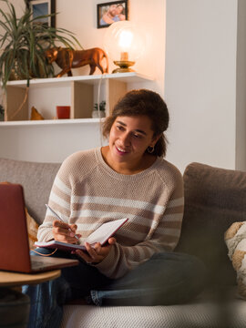 Woman writing notes while listening to coach online 