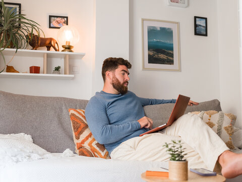Man Working on Laptop in Cozy Living Room During the Day
