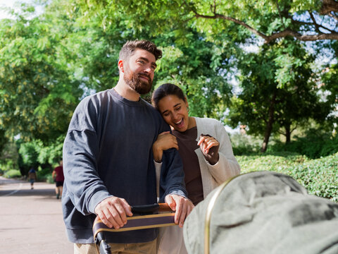 Parents enjoying park walk with baby stroller