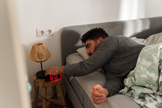 Man Wakes up and Turns off Alarm Clock in a Cozy Bedroom