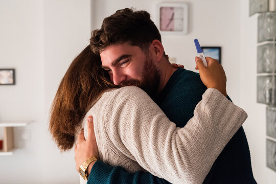 Couple hugging after getting positive pregnancy test result 