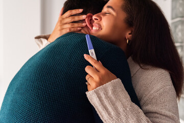 Excited couple celebrating positive pregnancy test result 