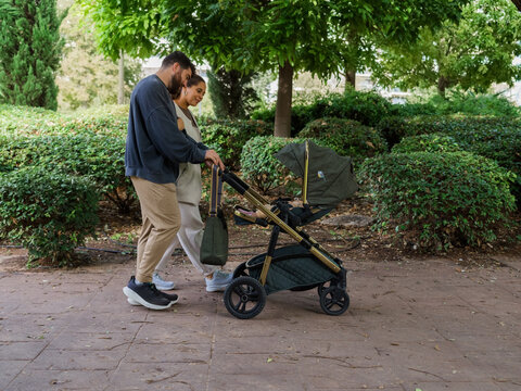 Parents watching their baby during stroll in park 
