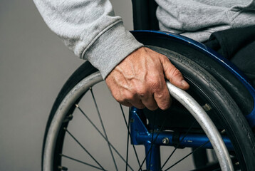 Obraz premium A person in a wheelchair, close-up view of hand gripping the wheel