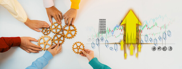 A group of hands work together to assemble gears on a table, symbolizing collaboration and growth...