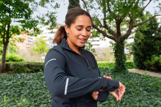 Woman Checking Fitness Tracker in Park During Morning Exercise