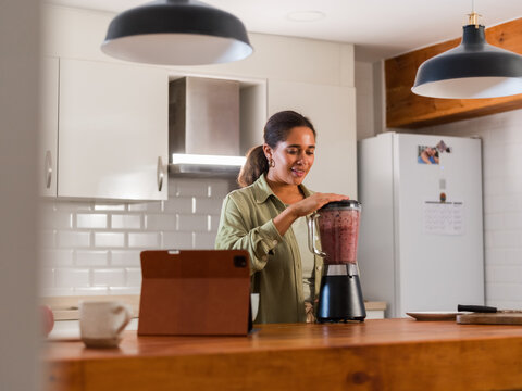 Woman making smoothie in blender