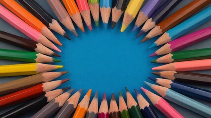 A vibrant circular arrangement of sharpened colored pencils on a blue background, tips pointing inwards, symbolizing creativity.