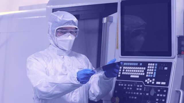 工場でシリコンウエハーを持つ防護服を着た作業員