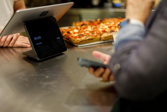 Woman paying at Local Pizzeria Using Mobile Phone