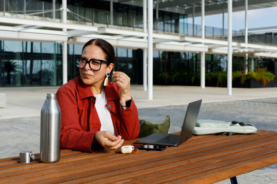 Woman With Laptop Working Outside in Front of Building