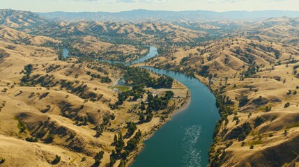 High-angle view of a winding river flowing through a landscape of tan hills