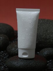 White tube of product with water droplets, on dark stones