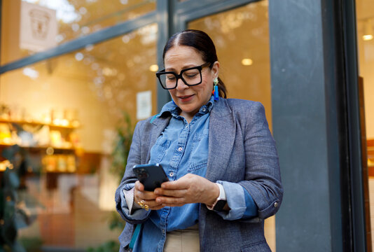 Woman Using Mobile Phone in Front of  Coffee Shop