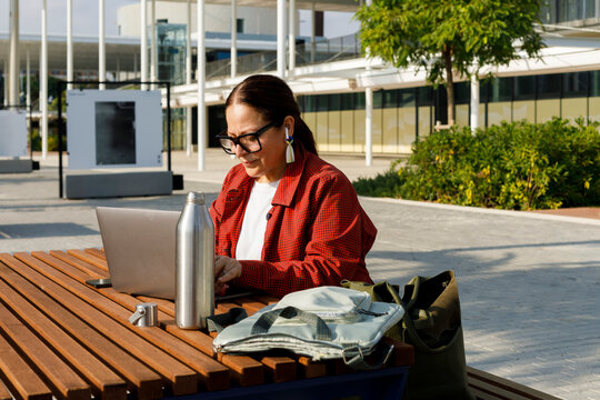 Woman Works on Laptop at Table in Outdoor Plaza
