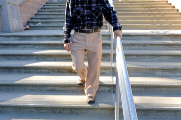 older man walks holding handrail