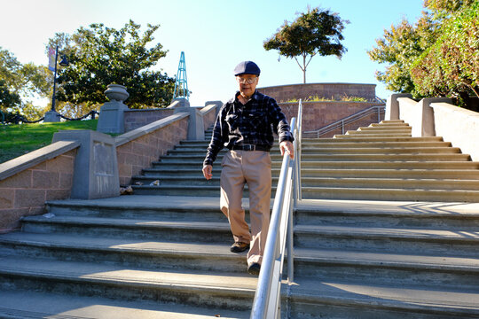older man walks holding handrail