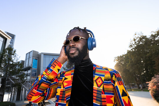 African man enjoying music with colorful fashion in city