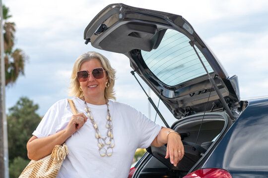 Smiling Woman Standing Near Her Car in Sunny Parking Lot