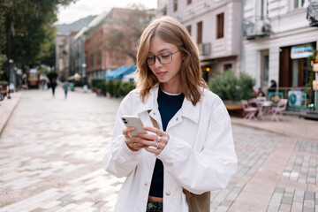 Woman checking her phone while walking in a lively urban location