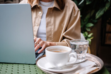 Working on a laptop while enjoying coffee and water at a cafe