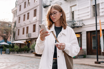 Young woman using smartphone on city street 