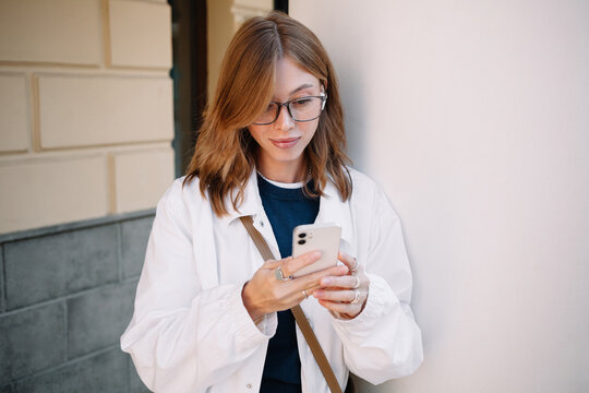Busy woman checking her phone while leaning against a wall