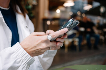 Person using smartphone while seated in a cozy indoor cafe