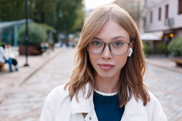 Young woman with glasses and earbuds enjoying a day in the park