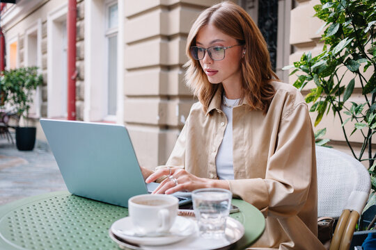 Young woman working on laptop at an outdoor cafe