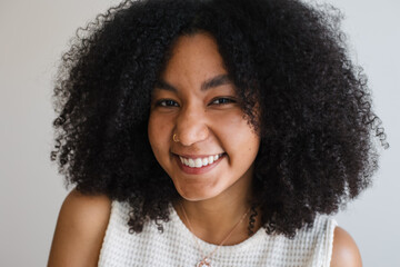 Candid portrait of a smiling woman with curly hair in a white to