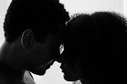 Candid moment of two lovers touching foreheads in a silhouette