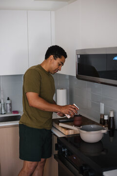 Candid home cooking: man seasons food in a modern kitchen