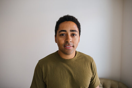 Candid portrait of a young man in a casual olive t&acirc;shirt indoo