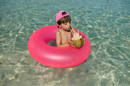 Kid Enjoying Coconut Drink in a Pool Float