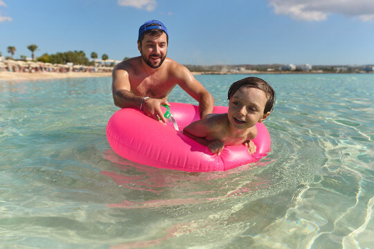Father Playing with Son in Inflatable Ring at Beach