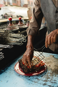 Street vendor grilling seasoned meat with onions and tomatoes