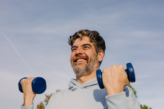 Older man lifting weights to strengthen his muscles