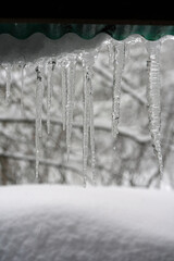 Close-up of long transparent icicles hanging from a roof in winter