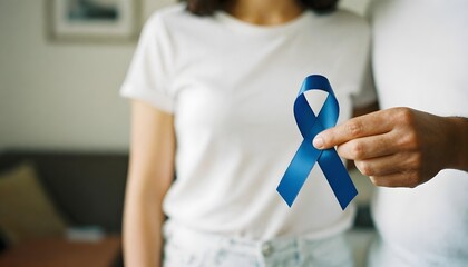 A woman displays a blue awareness ribbon, representing support for colorectal cancer during Colon Cancer Awareness Month in March
