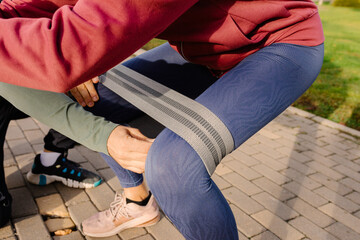 Trainer adjusting elastic band around legs of a mature adult woman