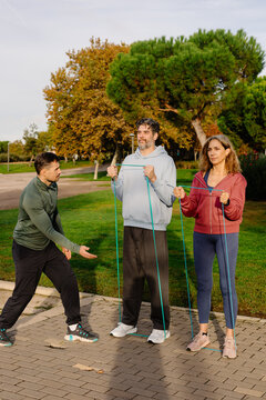 Instructor supports older couple during functional training exercises
