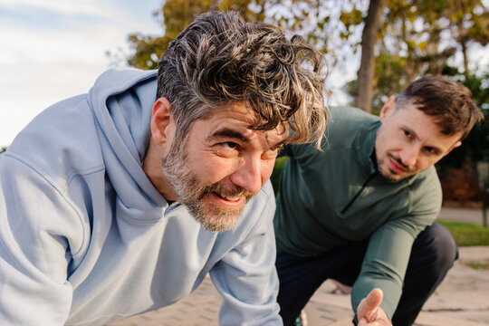 Senior does push-ups as his instructor encourages him during workout