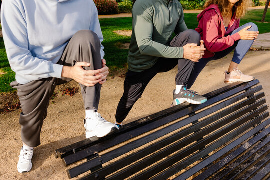 Anonymous trainer helps an active elderly couple perform stretches