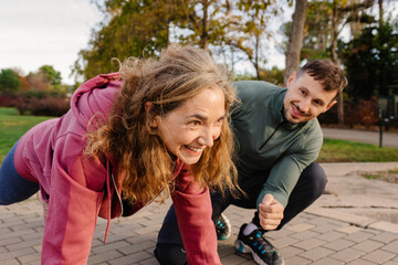 Woman does push-ups while her personal trainer motivates her