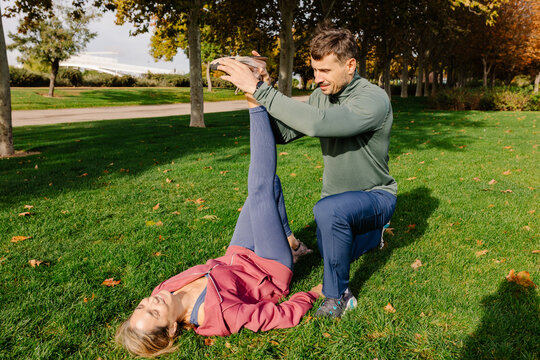 A personal trainer assisting a female mature adult with stretching
