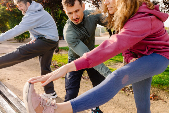 Personal trainer helps a mature adult woman with stretching