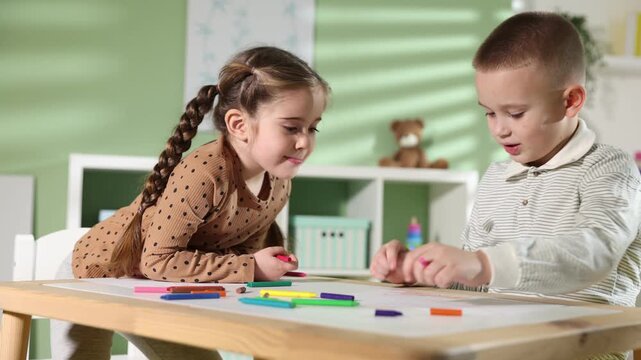Children drawing with crayons at table indoors