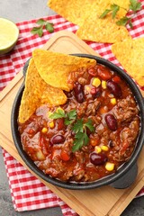 Plakat Delicious chili con carne served with nachos and lime on grey table, flat lay